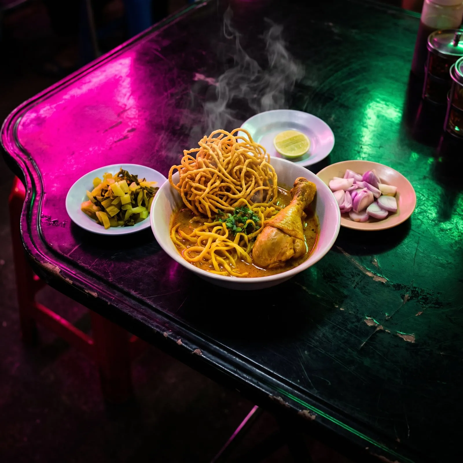 A bowl of khao soi curry noodles topped with crispy noodles and a chicken drumstick